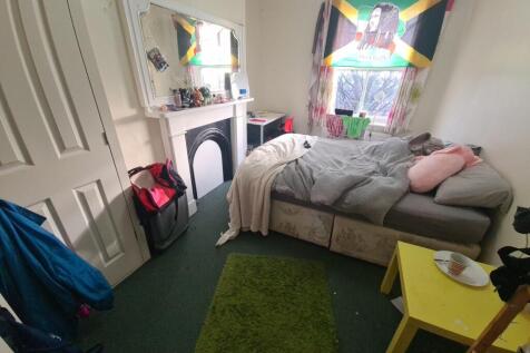 A cozy bedroom featuring a single bed positione...