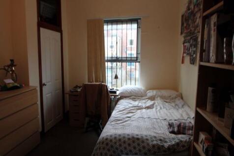 A cozy bedroom featuring a bed with a patterned...