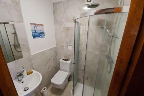 A modern bathroom featuring a glass-enclosed sh...