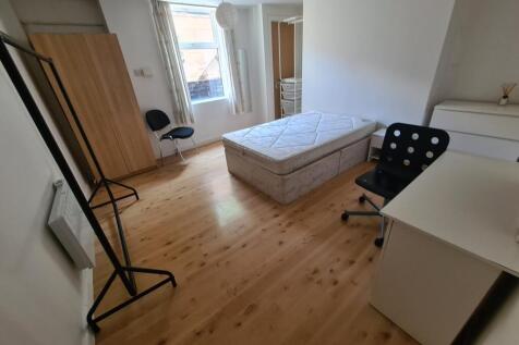 A bright, tidy bedroom featuring a single bed, ...