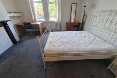 A bright, tidy bedroom featuring a comfortable ...