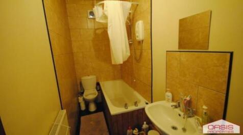 Tiled bathroom with a bathtub and overhead show...