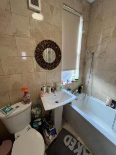 Compact, tiled bathroom with a bathtub and show...