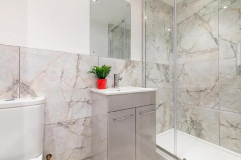 Modern, fully tiled bathroom featuring a glass-...