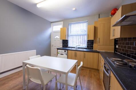 Bright modern kitchen with light wood cabinets,...