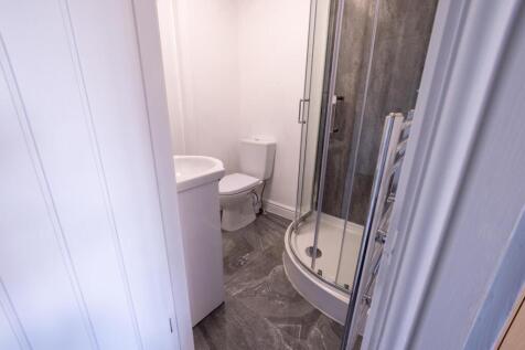 Bright, modern bathroom with a curved glass sho...