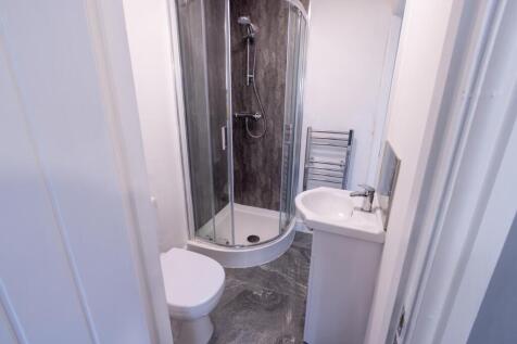 Modern compact bathroom featuring a curved glas...
