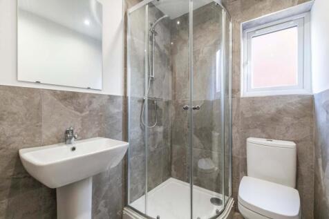 Bright, modern bathroom featuring a corner glas...