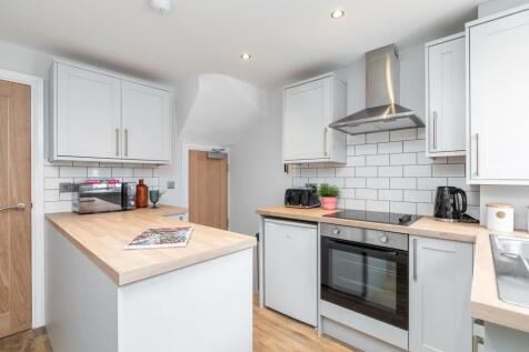 Bright modern kitchen with light cabinetry, woo...
