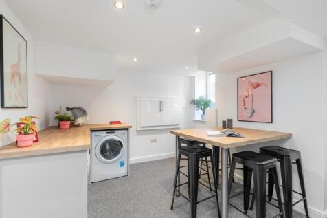 Bright, modern kitchenette with white cabinets,...