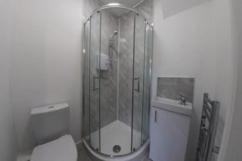 Modern compact bathroom with a corner glass sho...