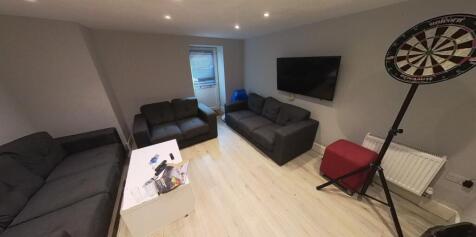 Bright, modern living room with multiple sofas,...