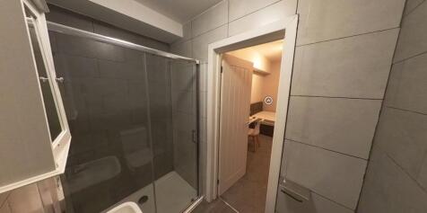 Modern bathroom with tiled walls, glass shower ...