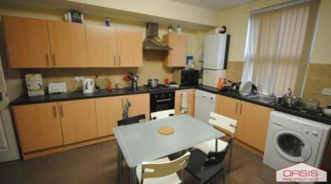 Well-equipped kitchen with modern light-wood ca...