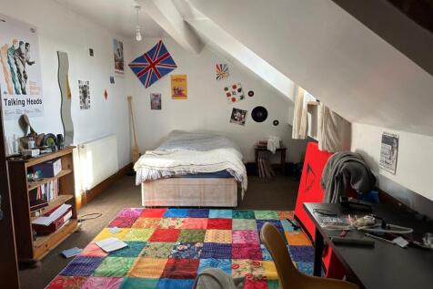 A cozy student bedroom featuring a large bed, c...