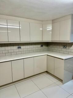 Modern L-shaped kitchen with glossy white cabin...