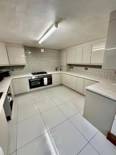Modern U-shaped kitchen with glossy white floor...