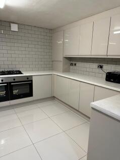 A modern, bright kitchen featuring sleek white ...