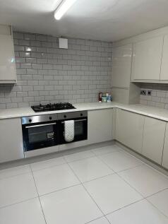 Modern, clean kitchen with white cabinetry, til...