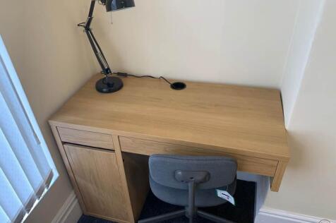 Compact furnished workspace with a light wood d...