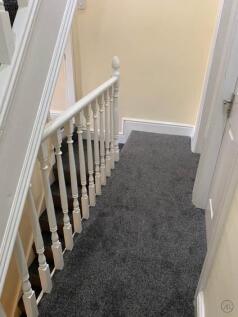 Bright carpeted upstairs landing with white ban...