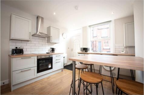 Bright, modern kitchen with white cabinetry, su...