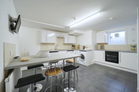 Bright, modern kitchen with white cabinetry, in...