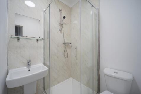 Bright, modern bathroom with a corner shower en...