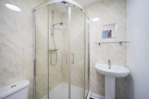 Bright, modern bathroom featuring a curved-glas...
