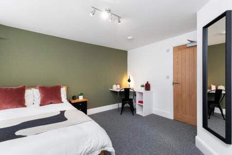 Bright, modern double bedroom with muted green ...