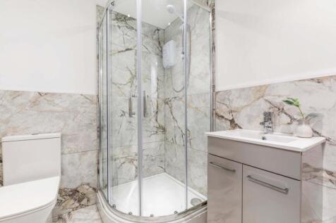 Bright, modern bathroom featuring a curved glas...