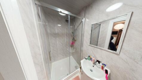 Bright modern bathroom with a corner glass show...