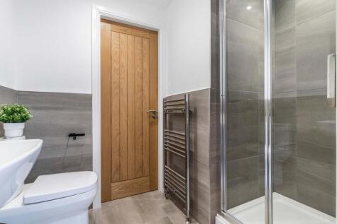Modern bathroom with tiled walls, a glass-enclo...