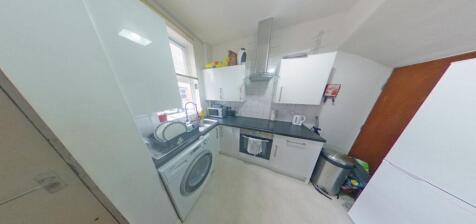 Bright compact kitchen with modern white cabine...