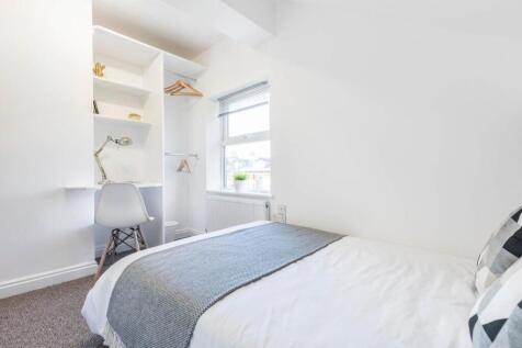 Bright, neatly styled bedroom with a comfortabl...