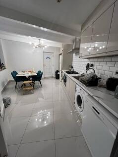 Bright, modern galley kitchen with glossy tiled...