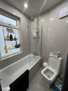 Modern tiled bathroom with a bathtub and overhe...