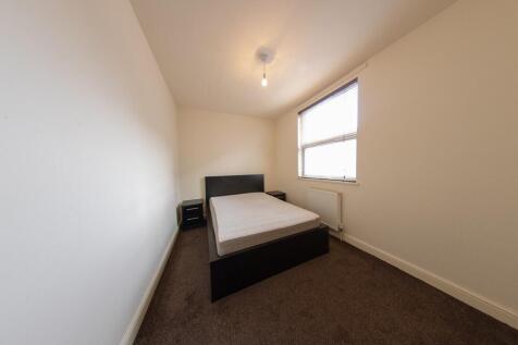 Neat, simply furnished single bedroom with a be...