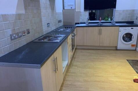 Modern fitted kitchen with light wood cabinets,...