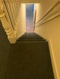 Narrow internal staircase with dark carpet and ...