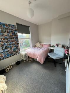 Bright, neatly kept bedroom featuring a comfy s...