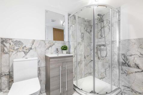 Bright, modern bathroom featuring a corner glas...