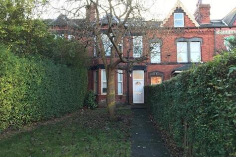 Red-brick terraced house set back behind a hedg...
