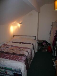 Cozy attic bedroom with a double bed positioned...