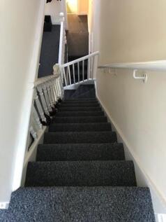 Well-maintained carpeted staircase with handrai...