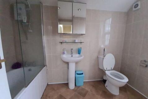 Bright tiled bathroom with a bathtub and shower...