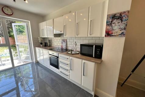 This modern kitchen features sleek white cabine...