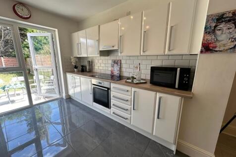 A modern kitchen featuring sleek white cabinets...