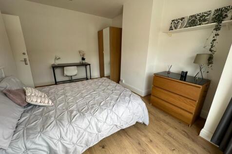 This spacious double bedroom features a comfort...