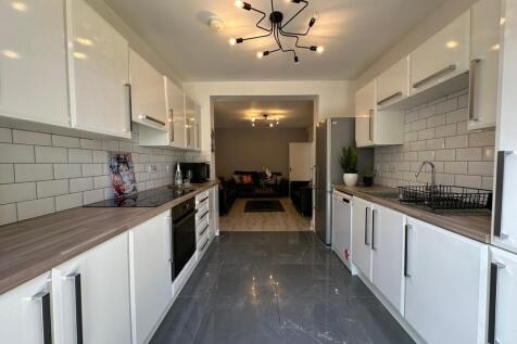 A modern kitchen featuring sleek white cabinetr...